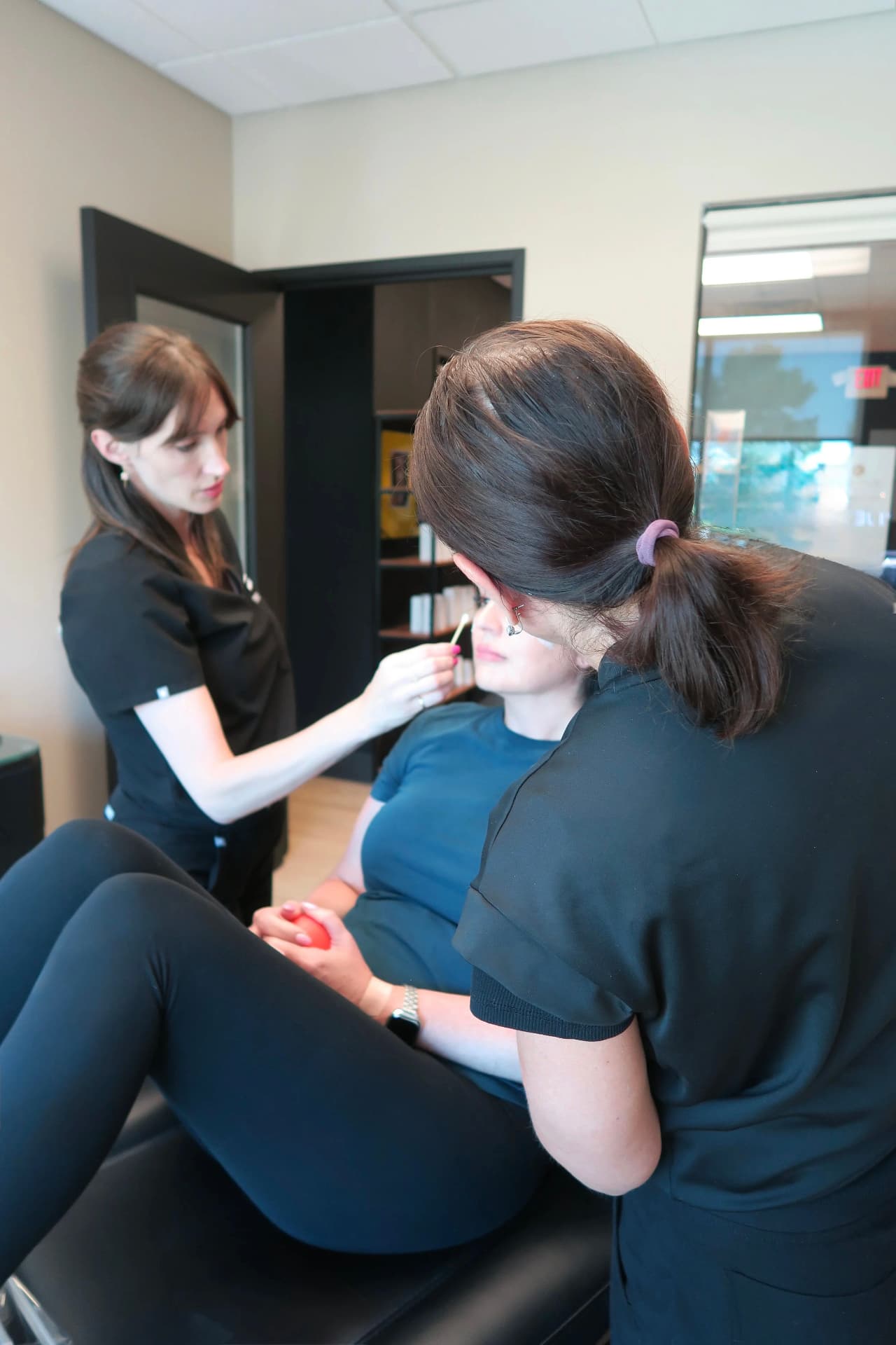 Two practitioners performing an aesthetic treatment on a client in a medspa room